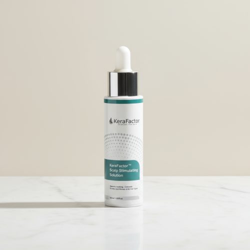 KeraFactor Scalp Stimulating Solution bottle on marble surface. Dermatologist-developed serum with peptides and growth factors that promote scalp health and fuller hair.