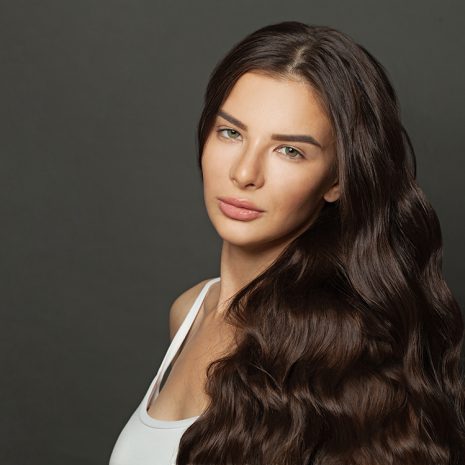Beautiful young woman with long curly hair on dark background